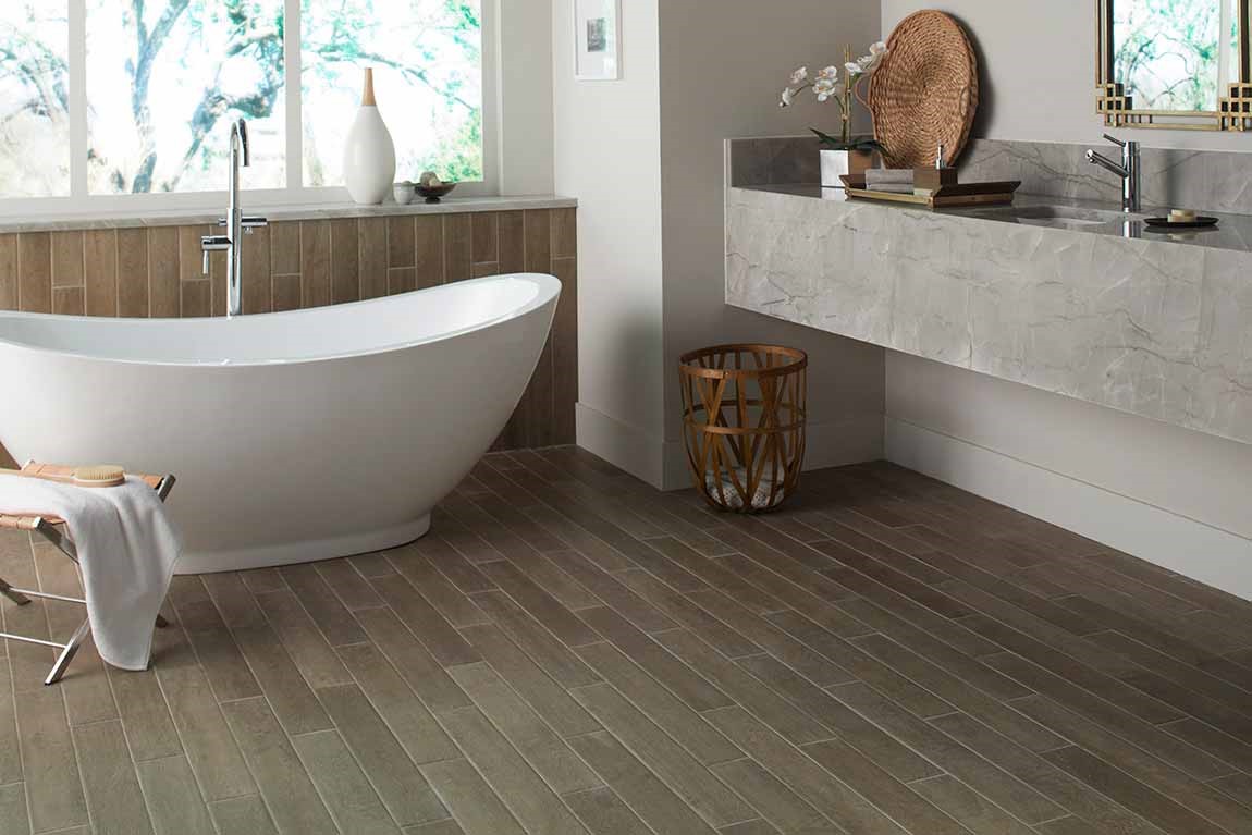 dark tiled bathroom with freestanding tub and floating vanity